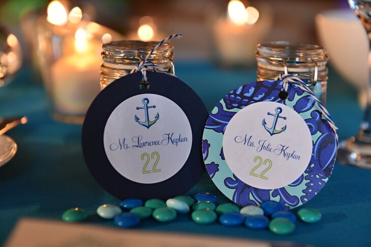 Guests found their seats through their circular blue and green escort cards, which had numbers depicted in green and an anchor design at the top. The circular escort cards hung from glass jars that each guest received and had M&M's sprinkled in front.