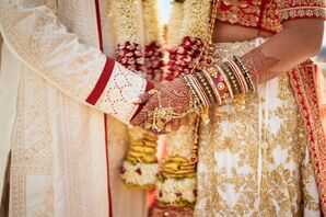 Indian Bride, Bangles and Henna, and Groom in Sherwani Hold Hands at Ceremony