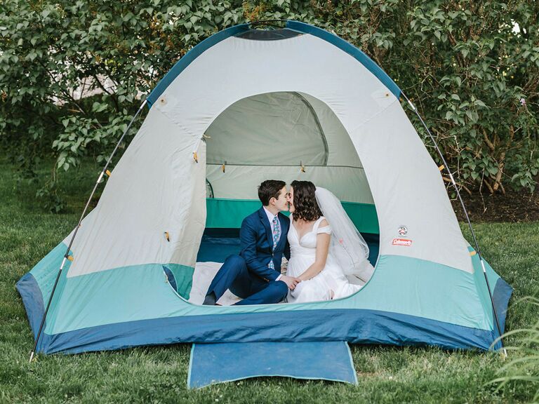 Bride and groom sitting in tent at camp-inspired outdoor summer backyard wedding