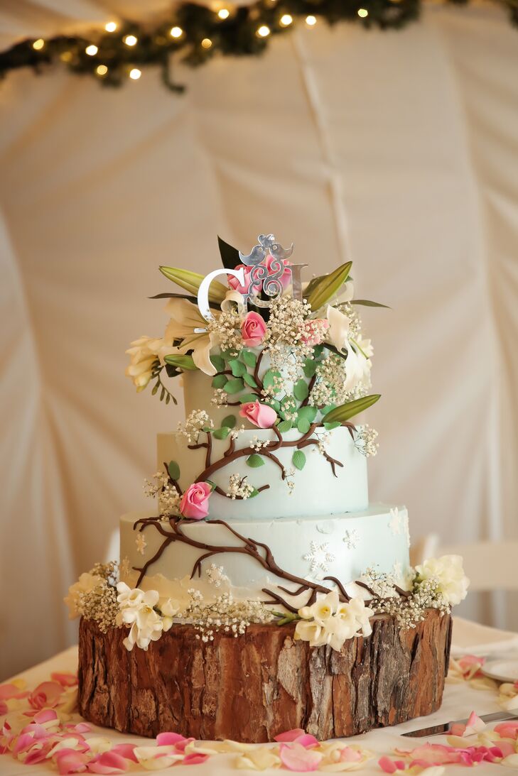 Julie and George designed their wedding cake with the help of Granite Bakery. The sky blue three-tier cake on a wooden slab had a tree climbing up the tiers with edible pink flowers and green leaves to give it a colorful, natural look. Fresh flowers and a bird topper completed the cake.