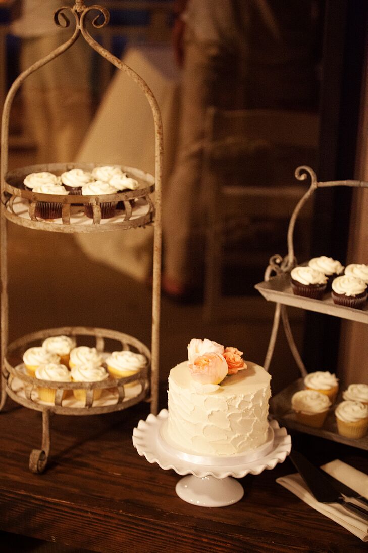 An ivory wedding cake filled with strawberry lemonade flavoring was served on a simple white cake stand. Vanilla and chocolate cupcakes were assorted on two wood tiers.