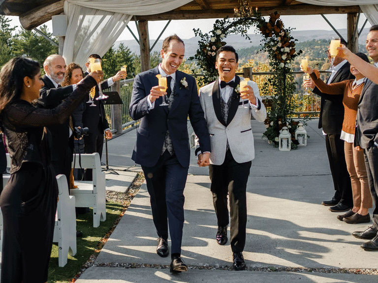 Grooms walking down the aisle as they toast their guests.