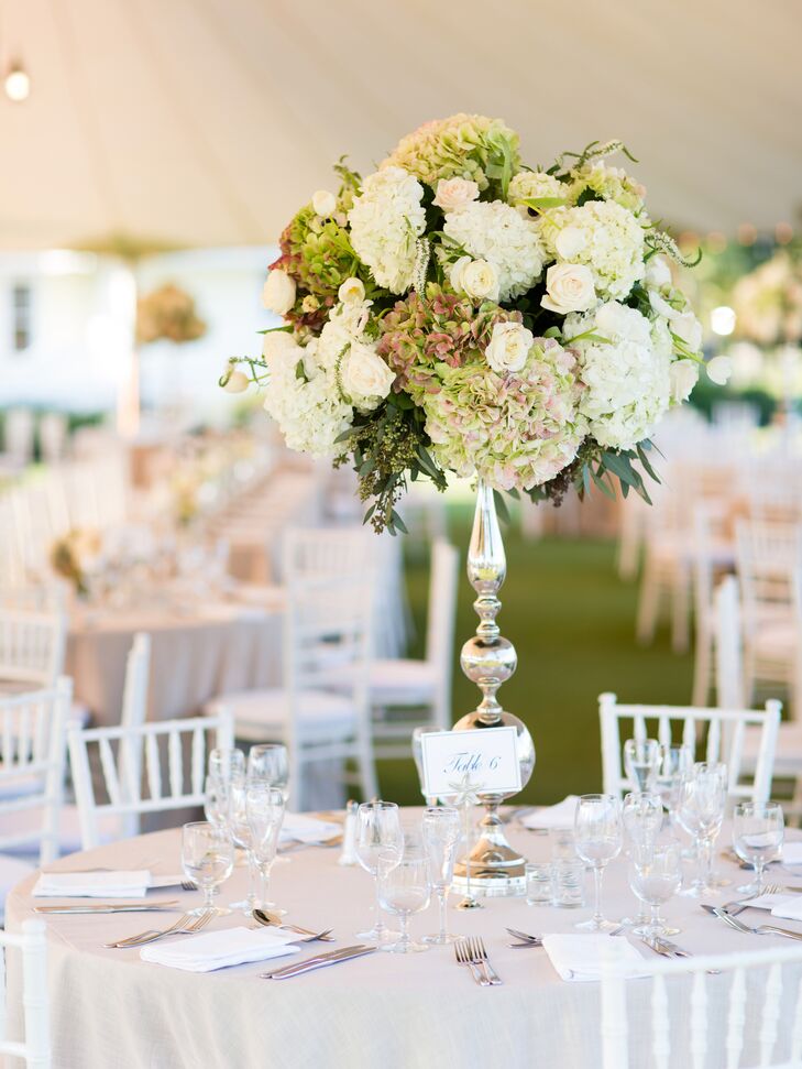 Tall glass candelabra vases held lush arrangements of white and green hydrangeas for the round table centerpiece decor.