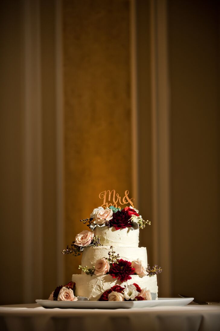Lauren and Phil put a sweet finish on dinner with a three-tier buttercream-frosted cake decked out in fresh blush roses and dramatic burgundy dahlias. The classic confection perfectly captured the couple’s vision for the day with its balance of rustic, romantic appeal, and whimsical calligraphy-inspired cake topper.