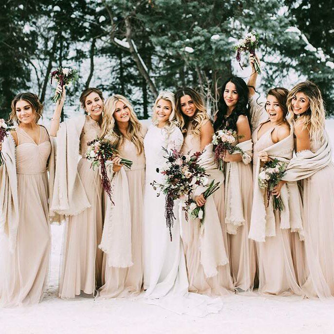 The bride and bridesmaids pose for the camera while holding beautiful bouquets. 