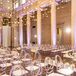 A ceremony space in the Baltimore Museum of Art featuring a hanging light installation, ghost chairs, elegant draping and minimalistic aisle decor with candles and low flower arrangements for a sophisticated, black-tie wedding.