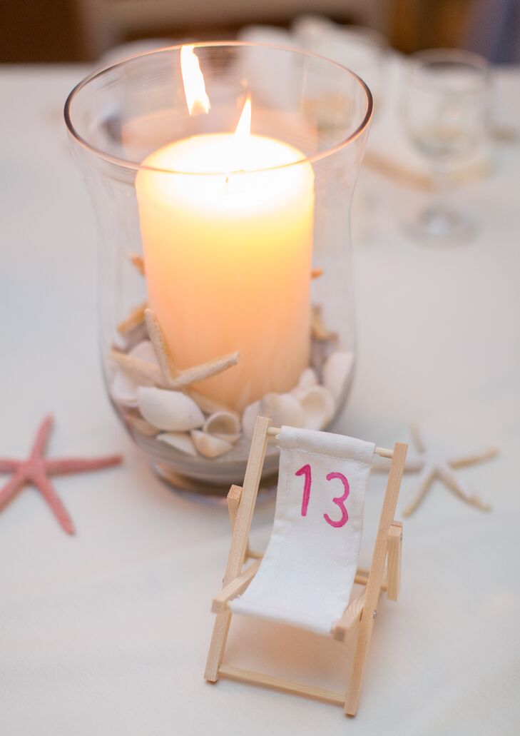 Playing up the wedding's beach theme, the table numbers were written on miniature beach chairs.