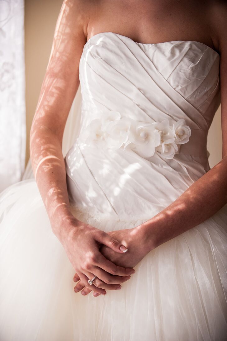 An ivory sash accented with fabric flowers wrapped around Haley's waist, to go with the color of her strapless Vera Wang ivory dress with a ball gown silhouette.