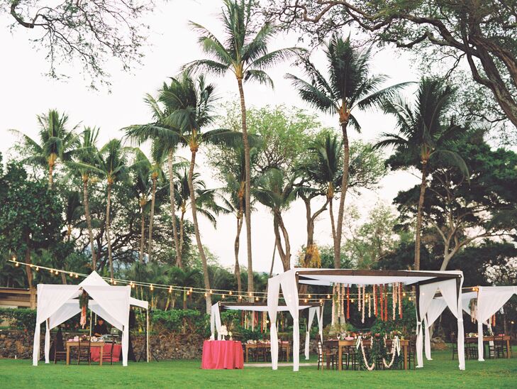 Guests sat at Kona wood farm tables under bistro lights and canopies draped with flower lei.