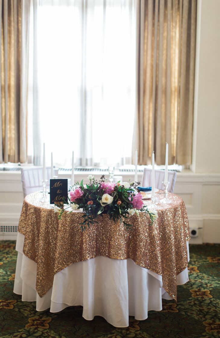 Their sweetheart table definitely stood out with a glitzy, gold sequin tablecloth. The seating was also decorated with white candlesticks, matching chair covers and a different centerpiece from the rest of their reception. It was filled with white roses, pink peonies, greenery, white freesia and seeded eucalyptus from Jim Ludwig’s Blumengarten Florist that cascaded over the table’s edge.