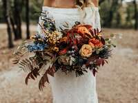 unique fall wedding bouquet with orange roses, greenery and red fall foliage