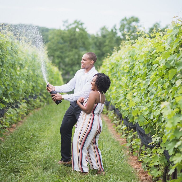 Couple sprays champagne during winery engagement session
