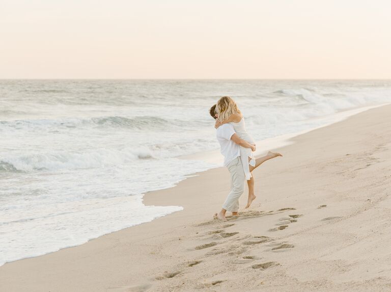 Couple embraces on a beach at sunset. 