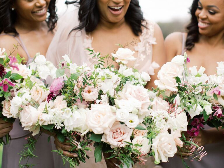 bride and bridesmaids stand side by side holding bouquets