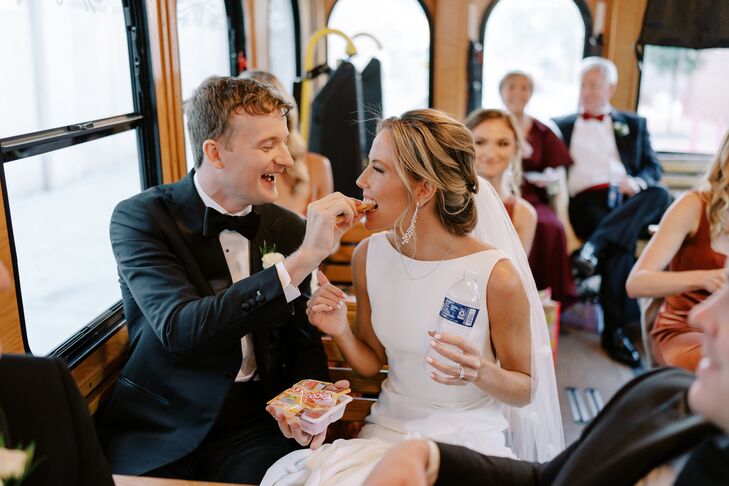 Groom Feeding Bride a Snack With Family on a Trolley Between the Ceremony and Reception