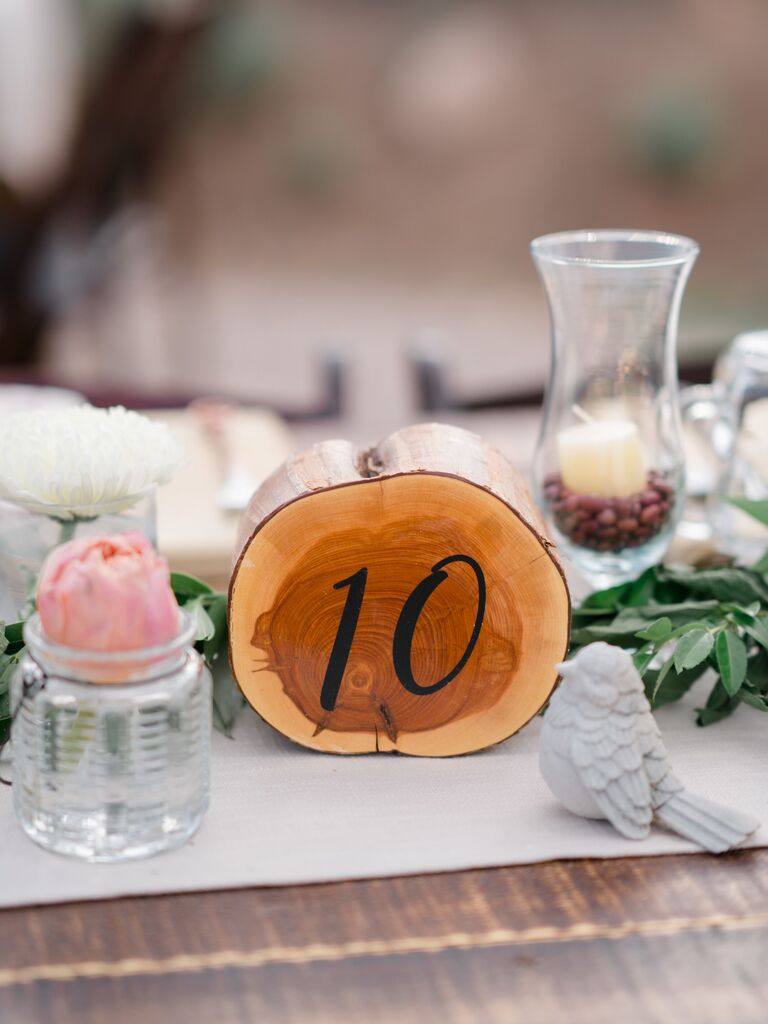 rustic wedding table number idea with number written onto sliced tree stump