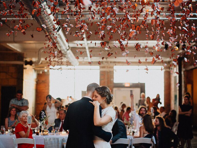 Couple dances with a monarch butterfly installation overhead. 