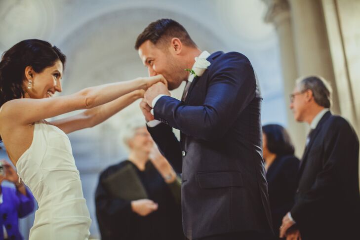 Groom Kissing Bride's Hands at Ceremony