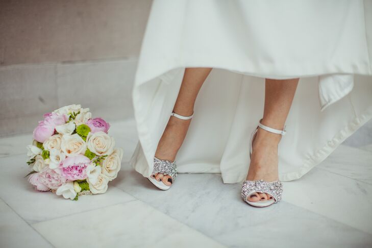 Jennifer stood wearing a pair of open-toed silver shoes with an ankle strap designed by Menbur, with a pastel bridal bouquet next to her.