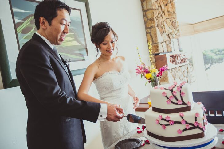 The bride and groom cut their ivory wedding cake decorated with a tree design that had pink flowers.