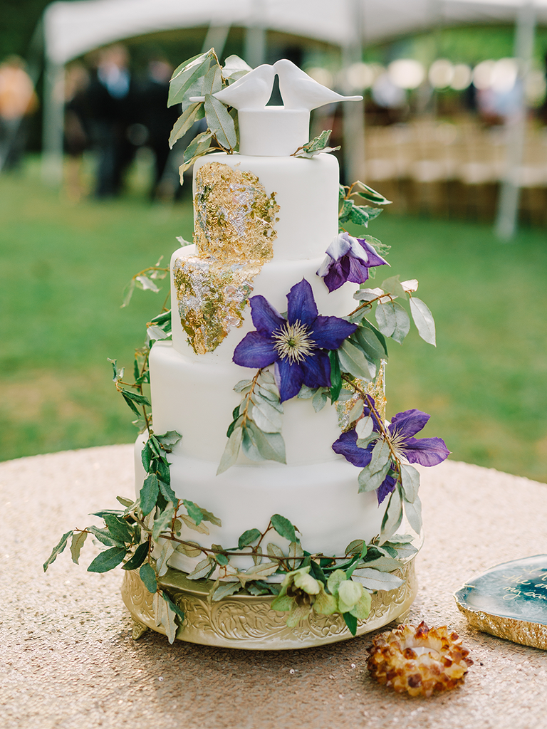Romantic wedding cake with purple clematis and gold foil designs