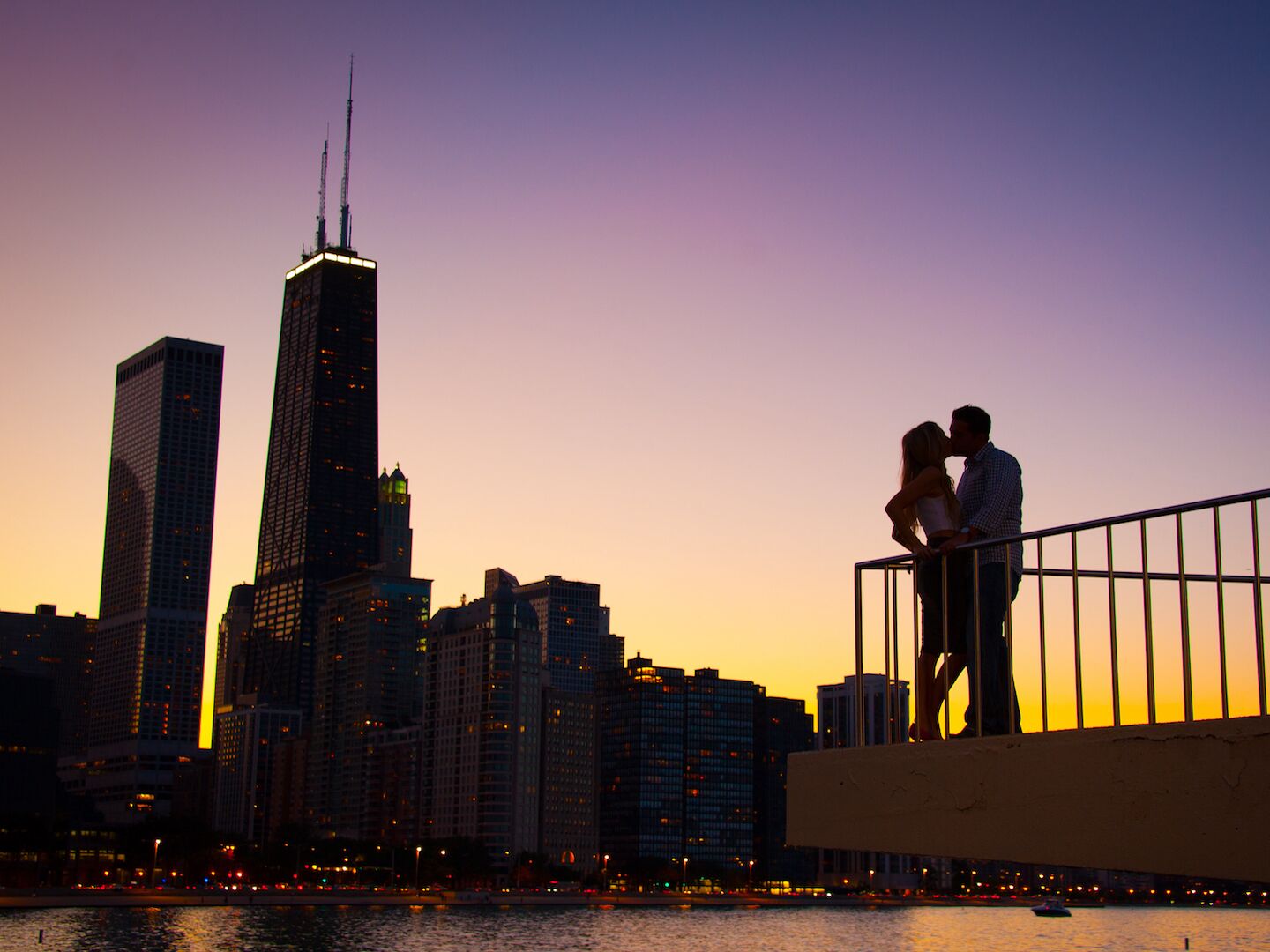 A couple kissing with the Chicago Skyline in the background during sunset.