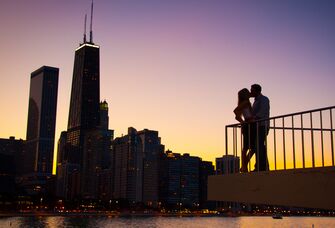 A couple kissing with the Chicago Skyline in the background during sunset.