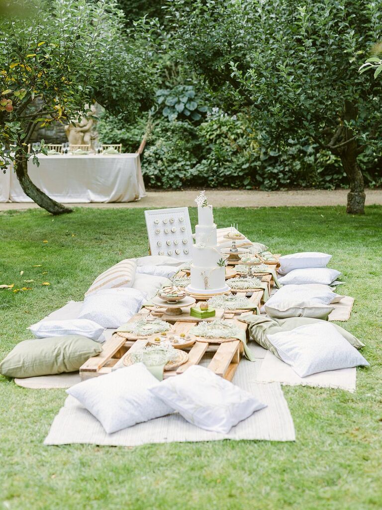 backyard picnic bridal shower with pillows and blankets in the grass surrounding a low wooden table