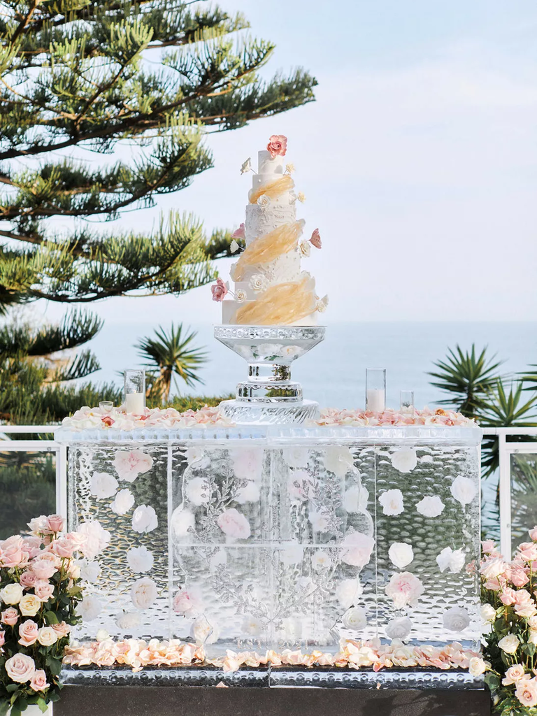A tiered wedding cake sitting atop a fantastic ice sculpture