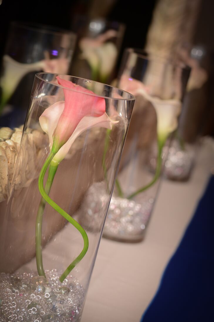 Pink calla lilies were arranged in white cylinder vases and decorated the reception at La Vera Party Center venue.