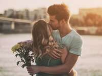 Woman and man embracing with flowers in the sunset
