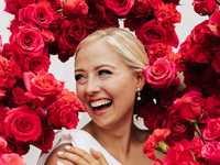 A bride smiles, surrounded by breathtaking pink floral arrangements.