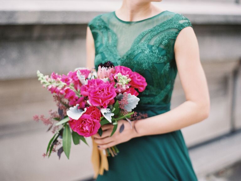 A bridesmaid holds a vibrant pink bouquet.