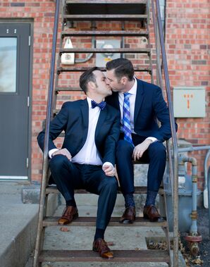 Two Groom's in Navy Suits Kiss Outside Alex Johnson Hotel