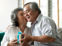Wife giving husband a gift and kiss on the cheek
