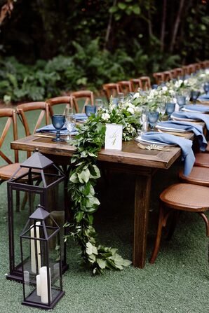 Wood Farm Table With Blue Napkins and Greenery Garland
