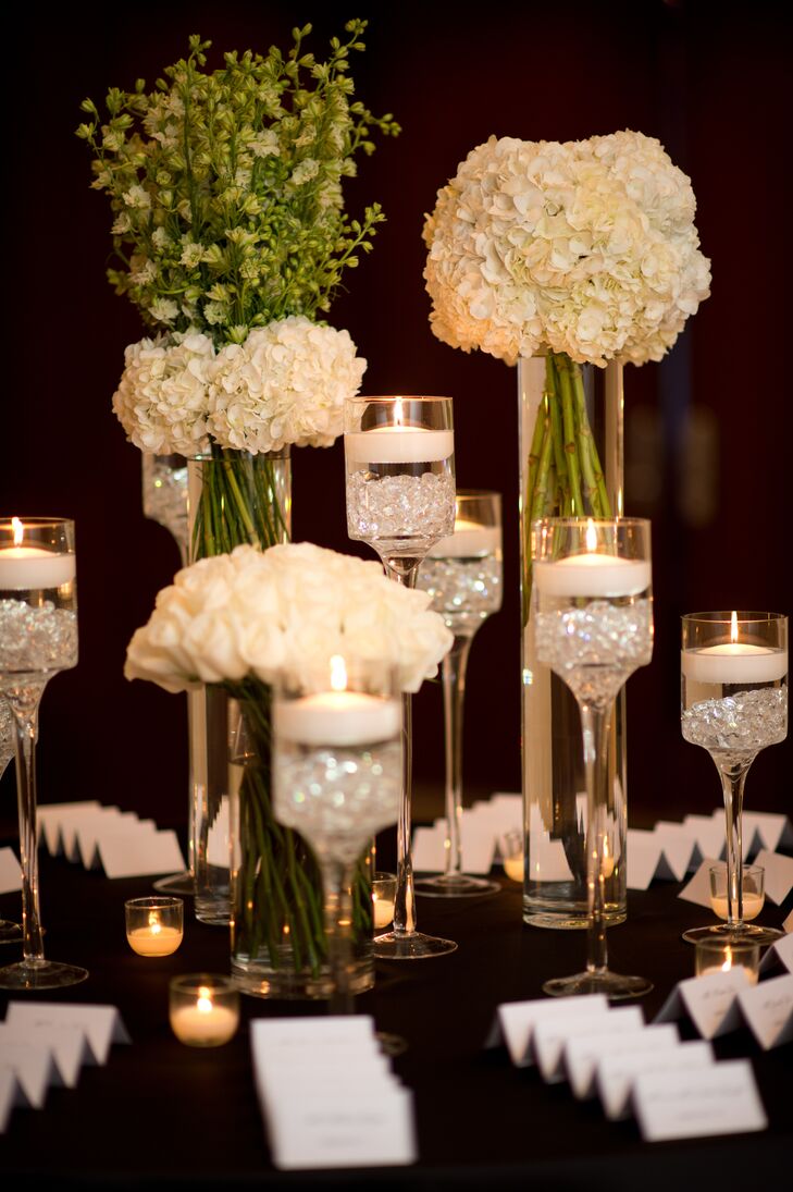Laura and Joseph's escort table was similar to their place settings, since it had high and low white floral arrangements  with tea candles and classic white escort cards sitting on it.