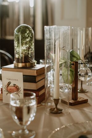 Eclectic Centerpiece With Books and Greenery-Filled Glass Cloche