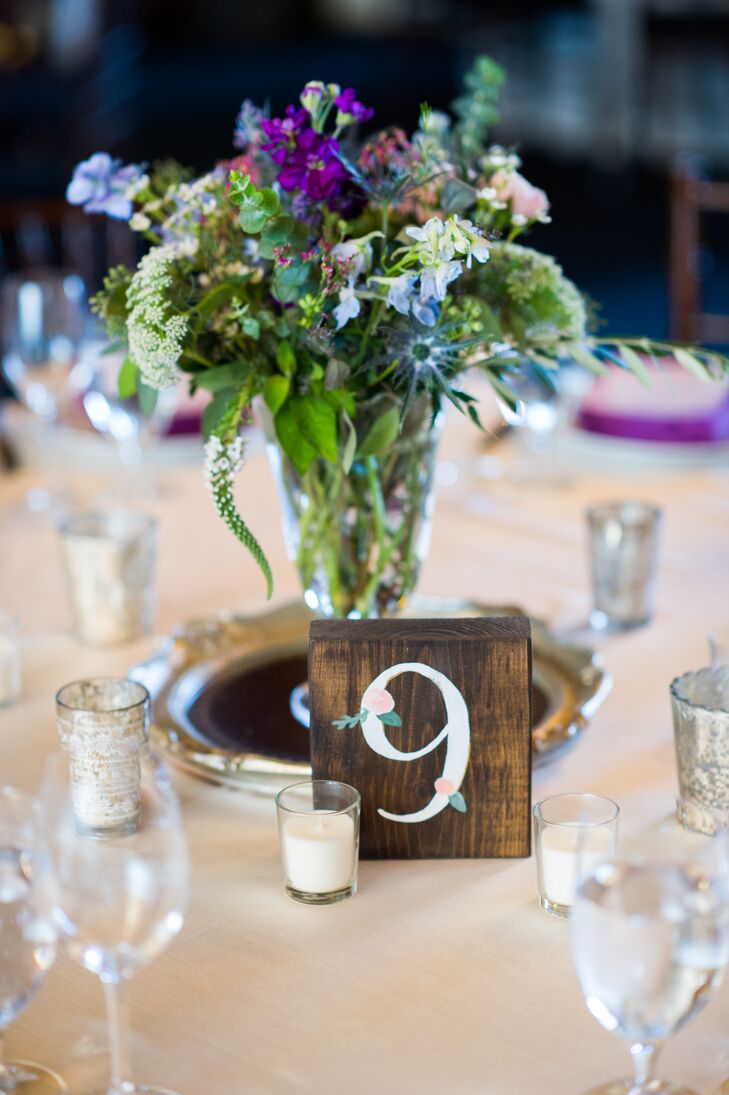 Centerpieces at Jennifer and Mario's reception consisted of a variety of wildflowers. Table numbers were written on wood blocks.