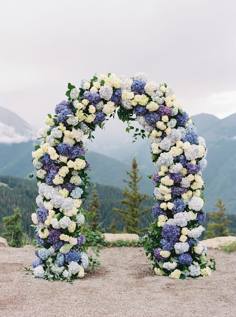 outdoor summer wedding ceremony arch with mountain backdrop and 2022 wedding colors veri peri blue and white hydrangeas 