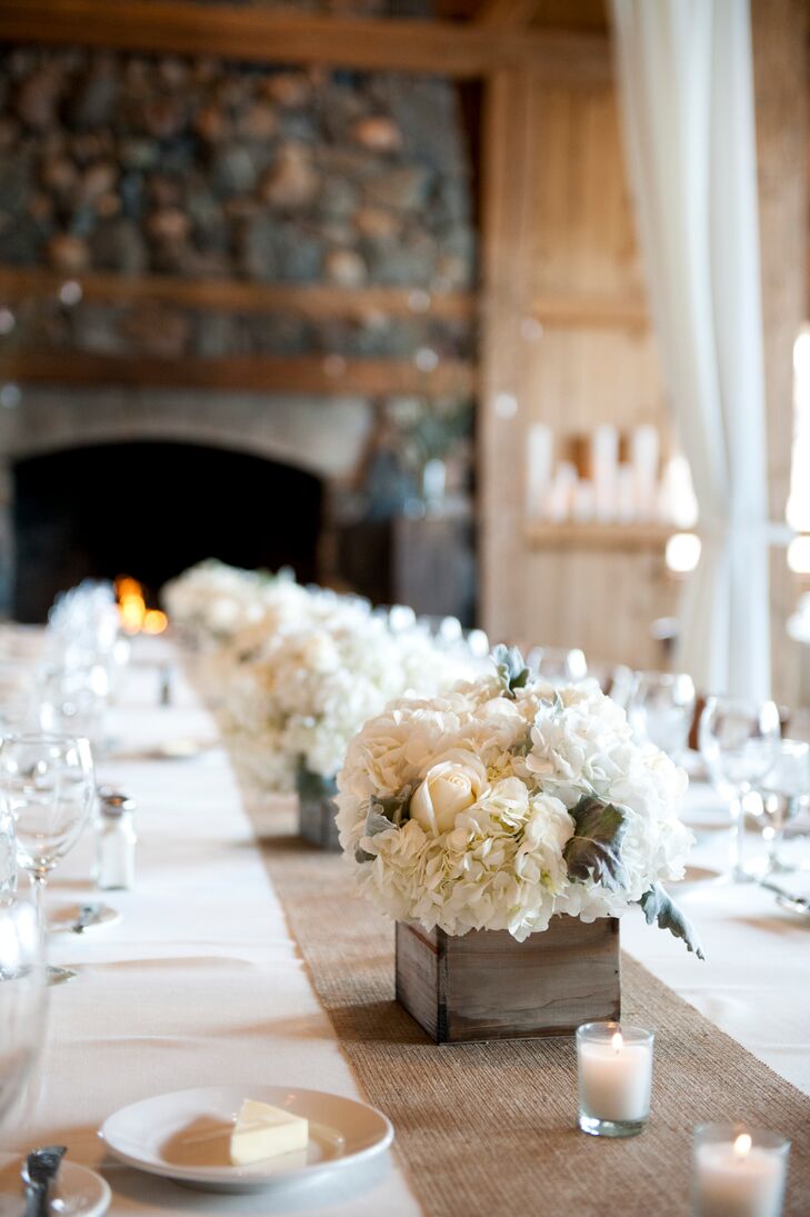 Each of the reception tables featured a different type of floral arrangement. The long reception tables were lined with cool ivory rose and hydrangea centerpieces arranged in rustic wooden boxes.