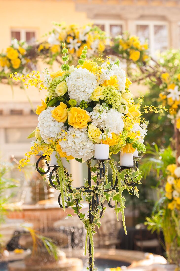 The couple lined their ceremony aisle with four 7ft. Victorian candelabras topped with English ivy, white candles, white hydrangea, yellow roses and yellow stock flowers.
