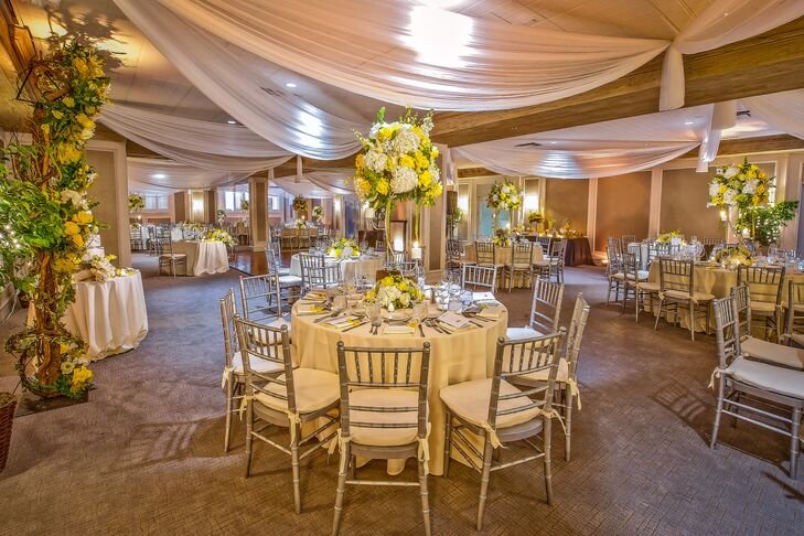 Terri and Matt decorated their reception with silver chiavari chairs surrounding each table ivory linens-covered round table. White fabric was draped overhead as a variety of low and tall white hydrangea and yellow rose arrangements were used as centerpieces.