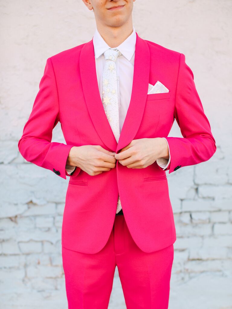 example of 2023 wedding color trend groom buttoning hot pink suit with white and gold star tie