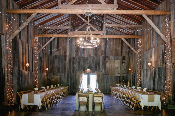 The exposed wood, rustic chandelier, drapery and string lights inside the Barn at Chestnut Springs  in Sevierville, Tennessee, made for a gorgeous reception spot. Katharine and Marc's guests sat at family-style dining tables and enjoyed a dinner of delicious Southern cuisine.