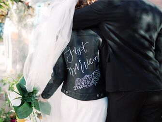 wedding couple bride wearing leather jacket with just married on the back