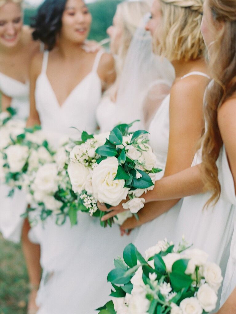 Bridesmaids in white dresses holding white wedding bouquets