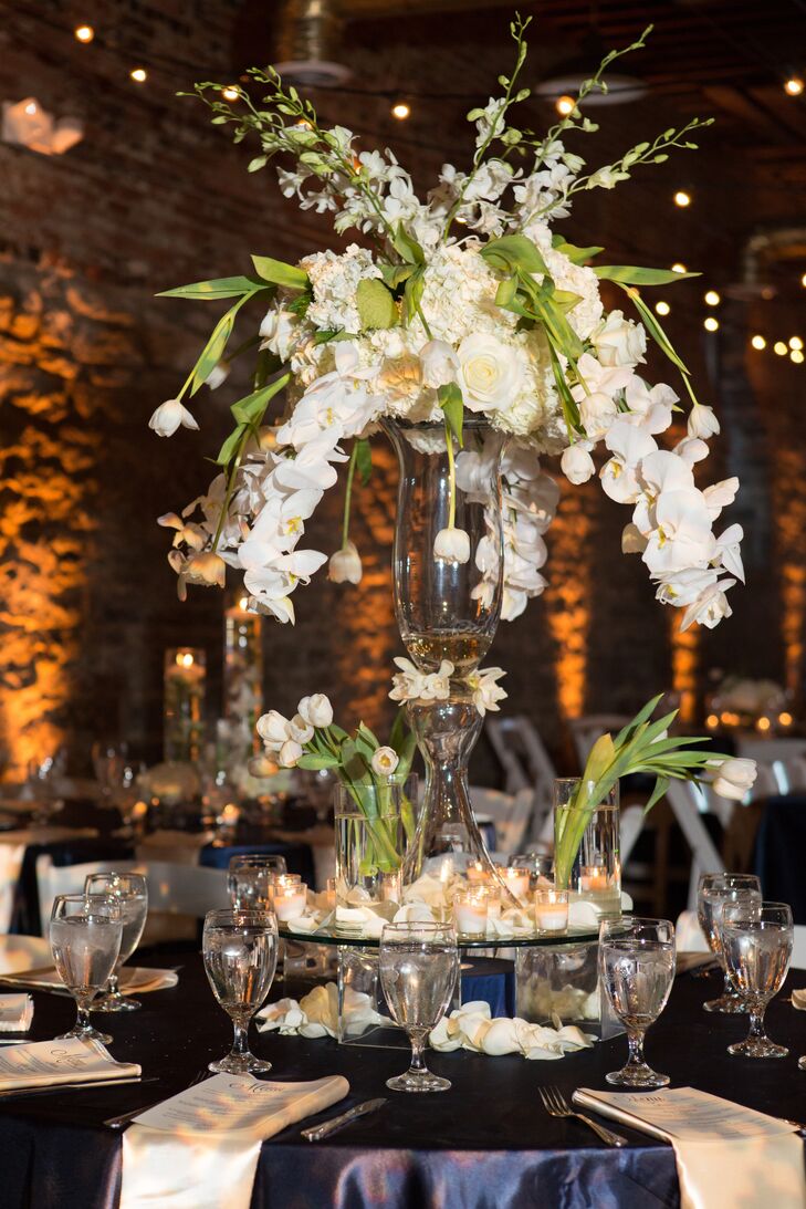 The couple worked with a navy blue and champagne color scheme paired with an abundance of contemporary white orchid and tulip centerpieces. "Because our wedding was in September, we wanted darker colors, but not necessarily the typical 'fall colors,'" says Suzie.