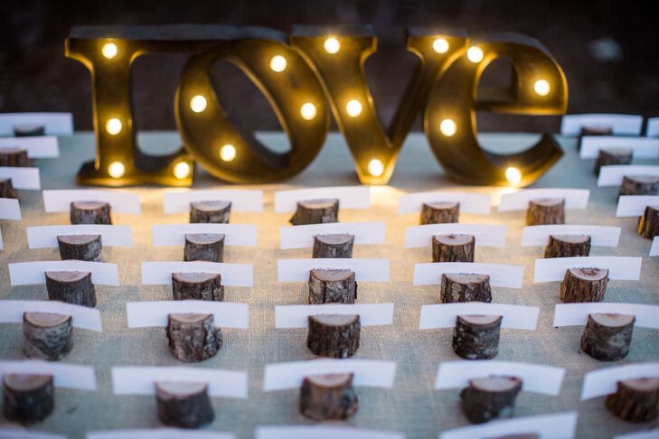 Each white escort card was wedged in a miniature log that served as a holder. Instead of listing a table number on each card, guests had to figure out where they were seated through three facts about the architectural building centerpiece that marked their table.
