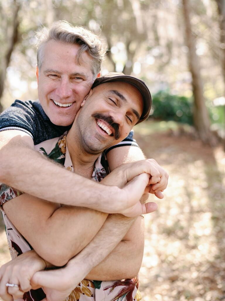 Couple smile while embracing in a hug. 